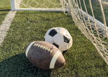 A football and soccer ball in a net